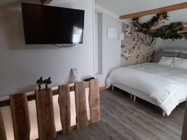 Un dormitorio con una cama, un televisor de pantalla plana montado en la pared, un banco de madera y una pared decorativa con flores.