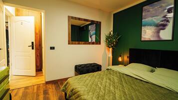 A bedroom with a bed, a nightstand, a mirror, and a door leading to another room.