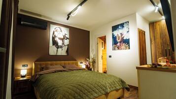 Een slaapkamer met een bed, nachtkastjes, een wandairconditioner en kunstwerken.