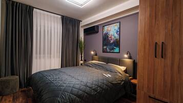A modern bedroom with a large bed, a wooden wardrobe, and a painting on the wall.