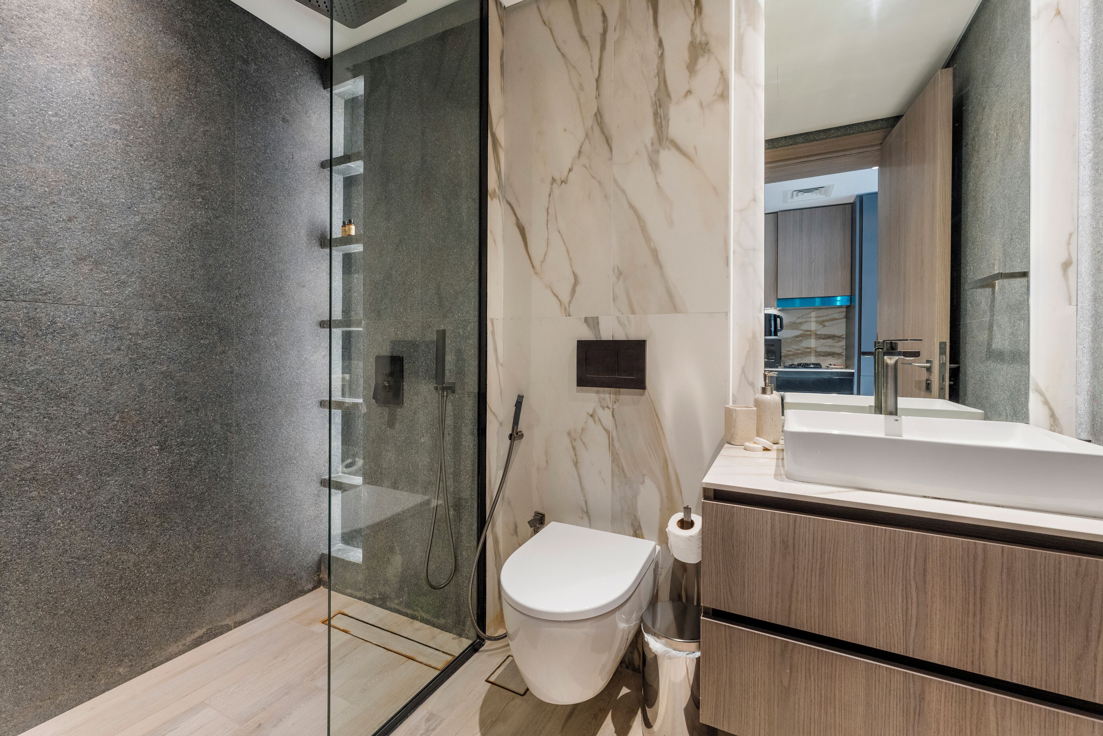 A modern bathroom with a glass shower enclosure, a toilet, and a vanity with a mirror.