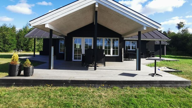 Une maison moderne dotée d’un patio couvert, de grandes fenêtres et d’une terrasse.