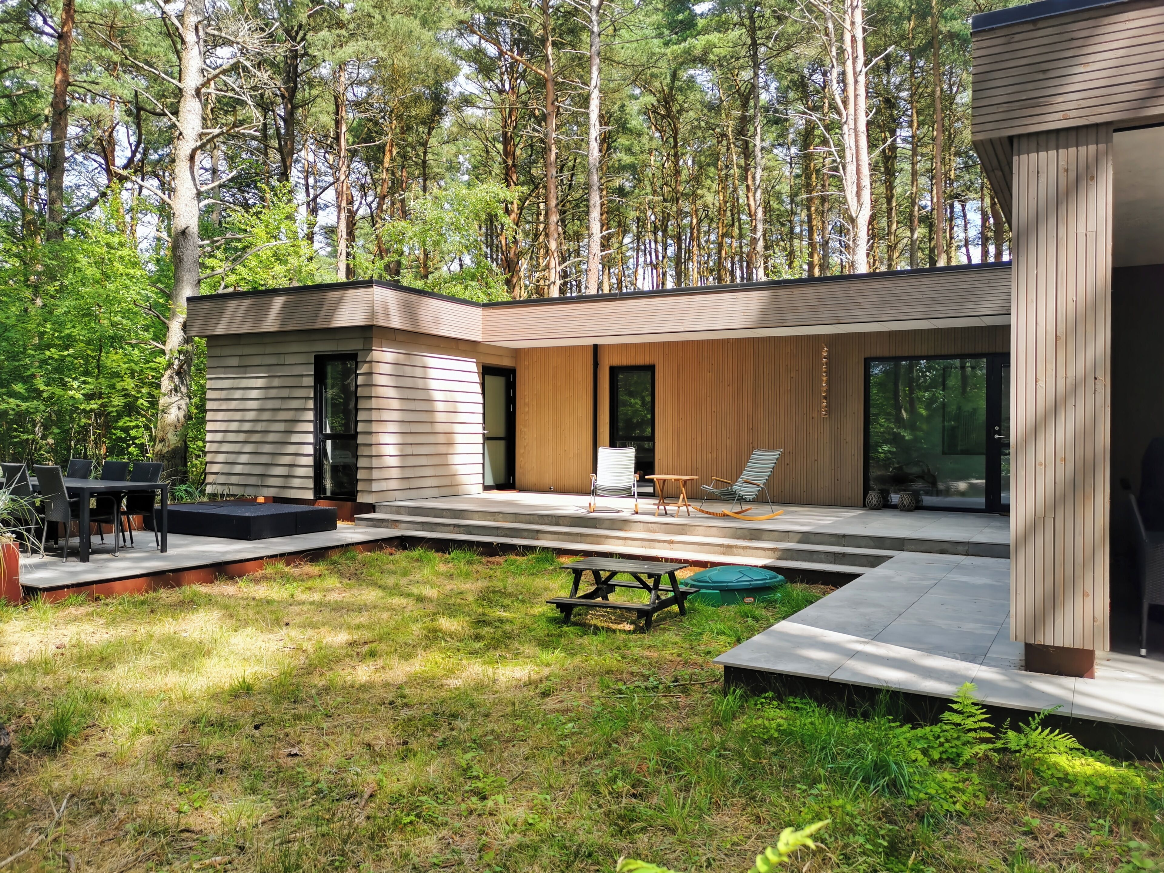 A modern house with a patio, outdoor seating, and a swimming pool.