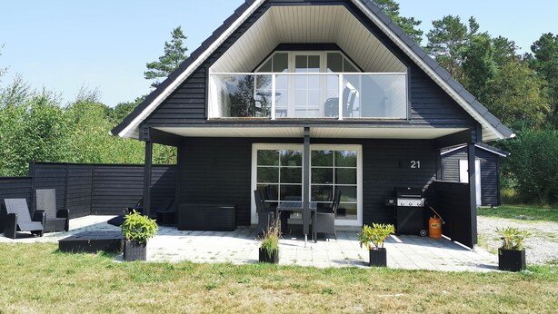 A modern two-story house with a balcony, a patio with outdoor furniture, and a grill area. - Modern Holiday Home With Nature Views in Læsø (Læsø)