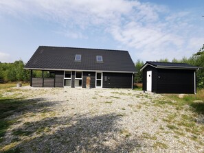 En modern byggnad i två våningar med ett mörkt tak och stora fönster.