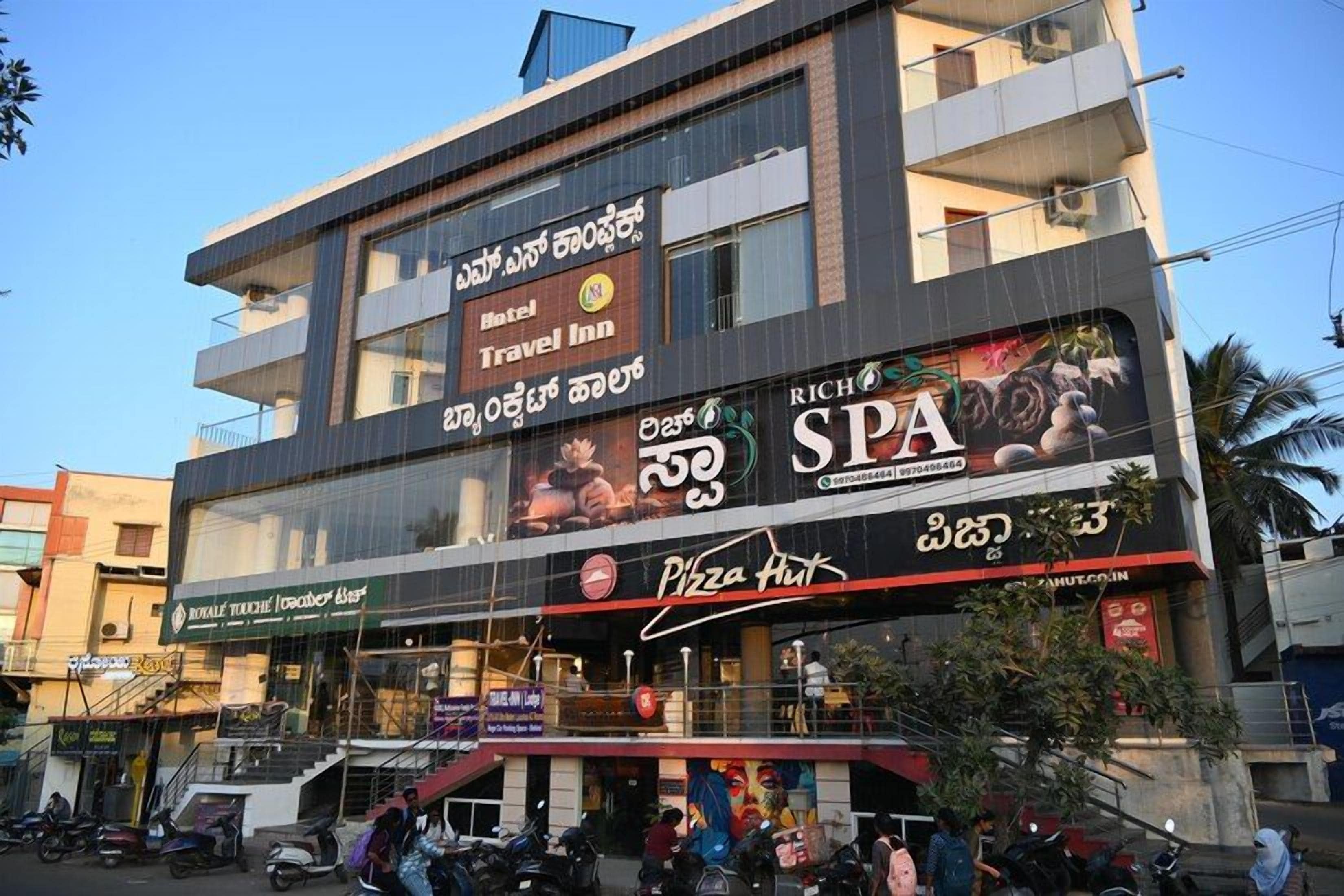 Un edificio de varios pisos con letrero de hotel, posada, spa y Pizza Hut.