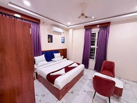 Una habitación de hotel con cama, escritorio, silla y ventana con cortinas.