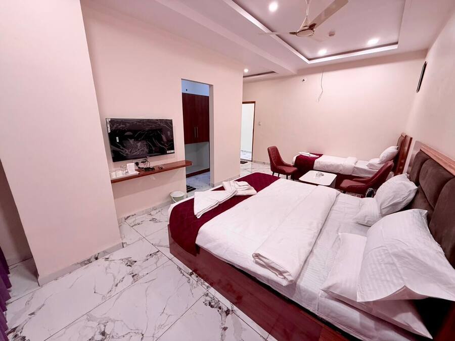 A hotel room with a large bed, a TV, a desk, and a chair.