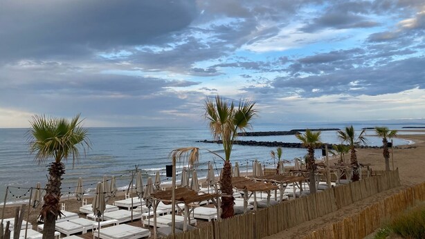 A beachside area with white lounge chairs and palm trees, overlooking the sea. - Comfortable mobile home in the south of France - perfect family vacation near the beach (Vias)