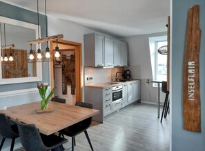 Eine moderne Küche mit weißen Schränken, einem Holztisch und einer Pendelleuchte.