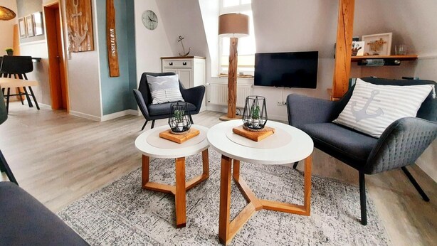 Un salon moderne comprenant un canapé, deux tables rondes, un téléviseur et un coin repas.