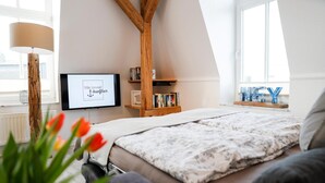 Une chambre à coucher avec un lit, une bibliothèque, un téléviseur et une fenêtre donnant sur un beau paysage.