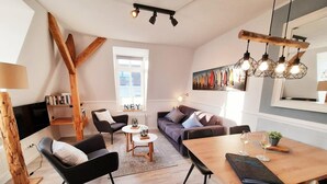 Un salon moderne comprenant un canapé, des fauteuils, une table à manger et une bibliothèque.