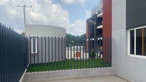 Een modern gebouw met een gebogen structuur, een omheind binnenterrein en een gevel in rood en grijs.