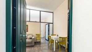 Ein Essbereich mit Tisch und Stühlen, einer Couch und einem Fenster mit Jalousien.