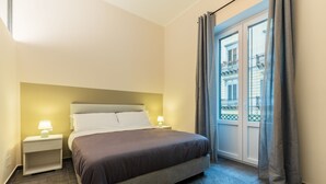 Ein ordentlich eingerichtetes Schlafzimmer mit einem Bett, zwei Nachttischen und einem Fenster mit Vorhängen.