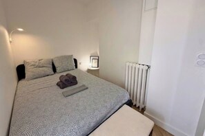 A neatly made bed with a patterned bedspread, a folded towel, and a bedside lamp. - Appartement de standing -centre- ville de Nice (Nice)