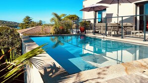A modern outdoor pool area with a clear blue pool, lounge chairs, and umbrellas. - Villa Livia swimming pool, Beach 500 m, sea view (Albitreccia)