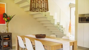 A modern dining area with a wooden table, white chairs, a decorative bowl, and a woven light fixture. - Modern 3-Bed Home with Pool Access, Ballito (Ballito)