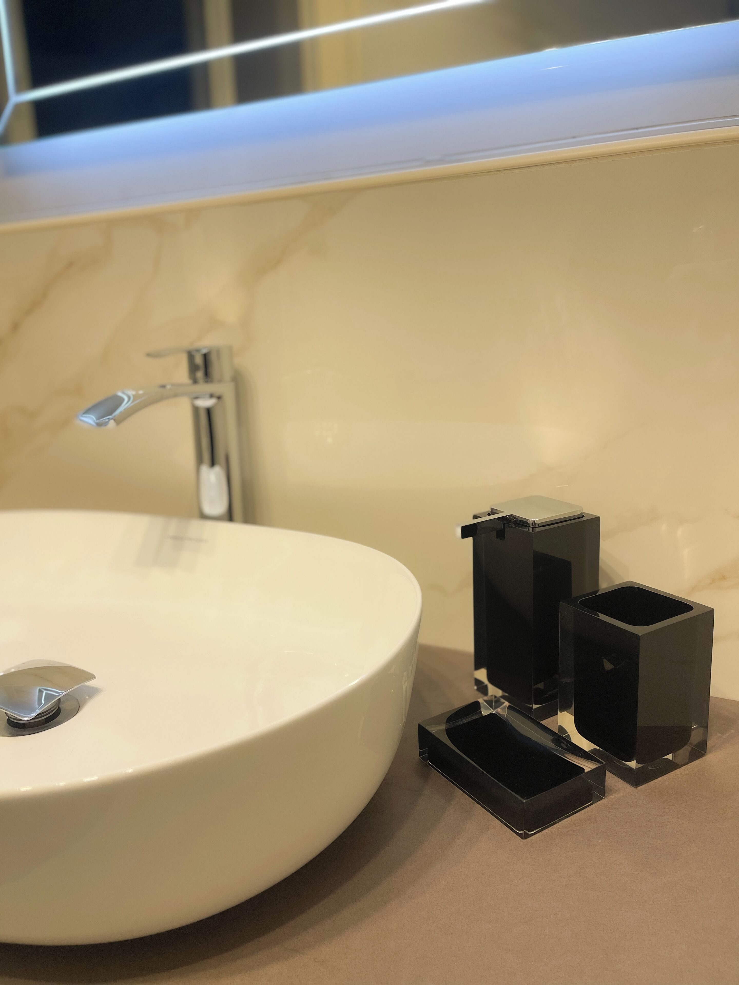 A bathroom with a white sink, a modern faucet, and black electrical outlets on the countertop.