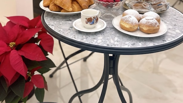 Een ontbijttafel met croissants, gebak, een schaal fruit en een kan sinaasappelsap.