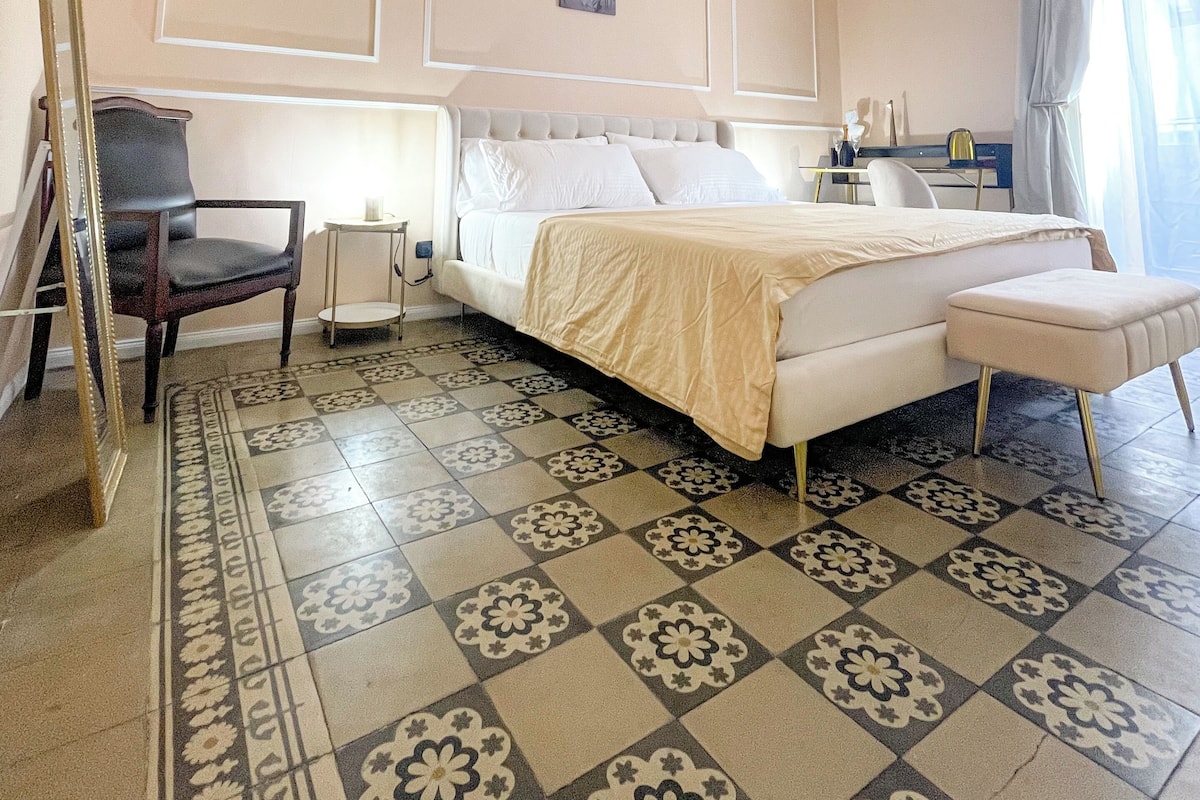 Una habitación de hotel con una cama, una silla, un escritorio y un espejo.