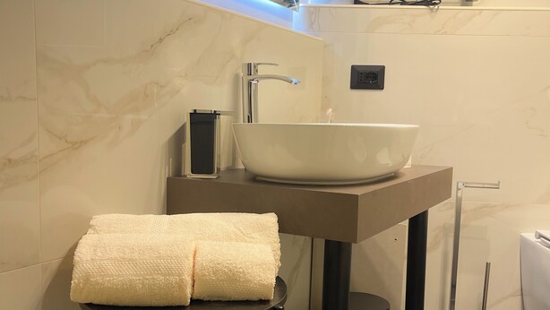 Une salle de bain moderne avec un grand lavabo blanc, un miroir et un porte-serviettes.