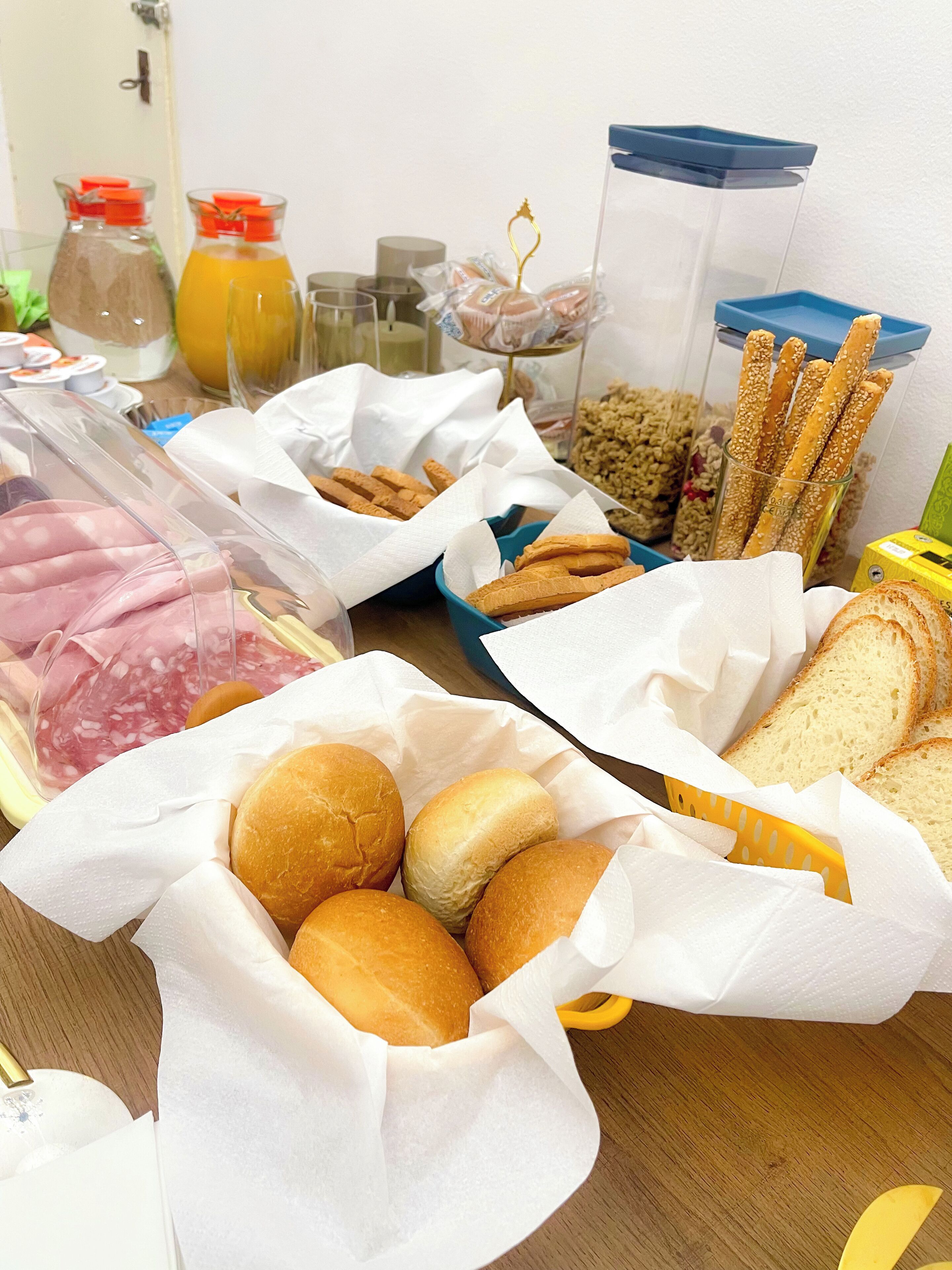 Una mesa con diversos alimentos, incluyendo pan, bollería y salsas.