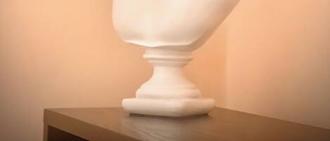 Una escultura de busto sobre un pedestal frente a una pared lisa.