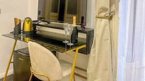 Een moderne kamer met een glazen bureau, een flatscreen televisie, een goudkleurige koffiezetapparaat, twee wijnglazen en een fles champagne.