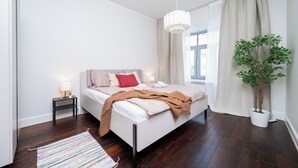Une chambre à coucher moderne avec un lit, une table de chevet, une lampe et une plante en pot.