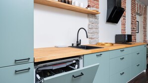 Une cuisine moderne avec un plan de travail en bois, un évier noir et un lave-vaisselle.