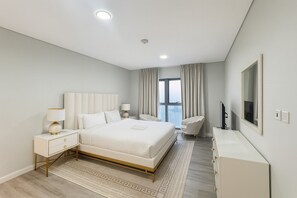 A modern hotel bedroom with a large bed, bedside tables, a desk, and a chair. - Stylish 2-Bedroom Apartment-Amazing view of JBR and Marina on high floor (Dubai)