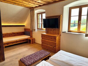 Une pièce chaleureuse avec un banc en bois, une commode, un téléviseur et une fenêtre donnant sur l’extérieur.