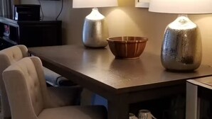 Camera d'albergo con tavolo da pranzo, due sedie, televisore e minibar.