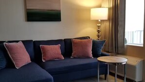 Un divano blu scuro con quattro cuscini, un tavolino rotondo, una lampada e un termosifone.