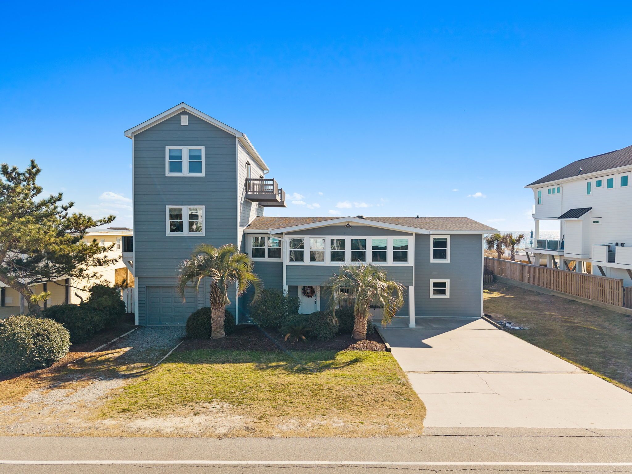 A two-story residential building with a balcony, a garage, and a well-maintained lawn.