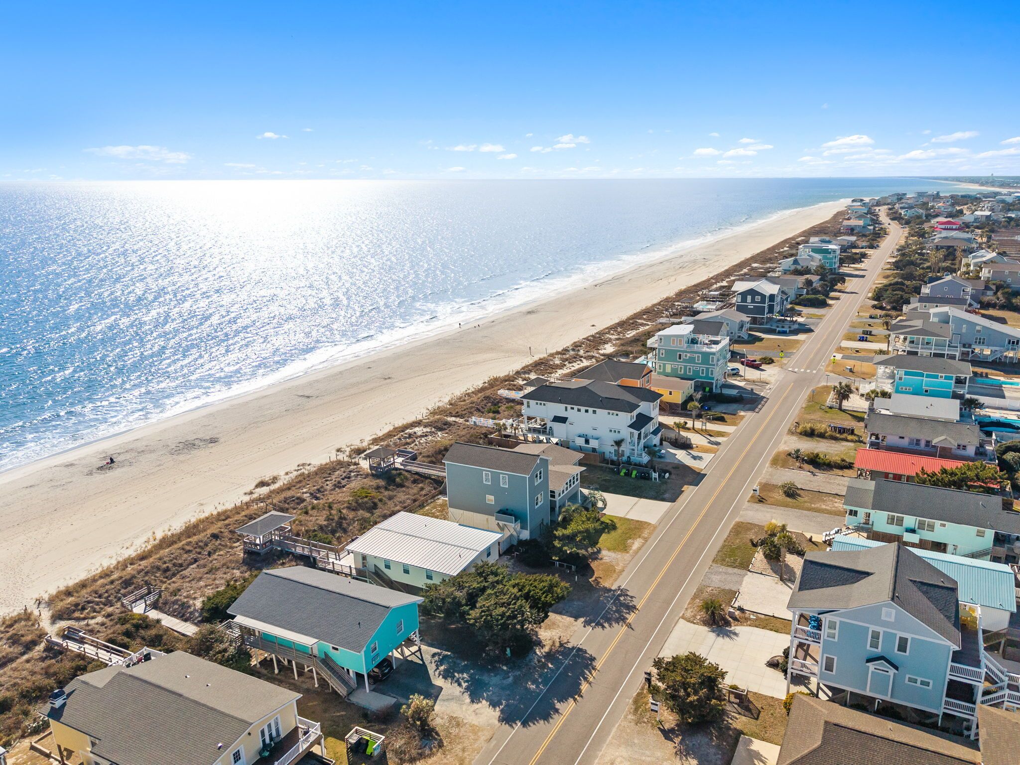 Vista aérea de una zona residencial costera con casas, una playa y una carretera.