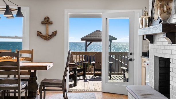 Una habitación con una mesa de comedor, sillas, una chimenea y vistas al océano.