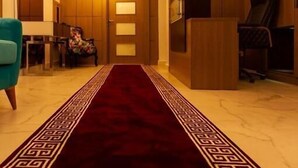 Un hall d’hôtel moderne avec un tapis rouge, des lambris en bois et un escalier.