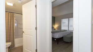 Un dormitorio con cama, mesita de noche, lámpara y ventana con persianas.