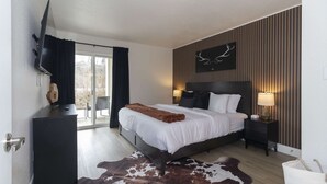 Habitación de hotel con cama, televisión, escritorio, lámpara y alfombra de cuero de vaca.