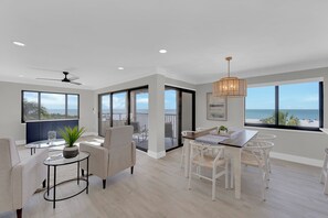 A modern interior with a dining area, seating, and a view of the beach. - Beachfront 2B/2B Sandarac Vacation Condo 506B. Direct gulf view! (Fort Myers Beach)