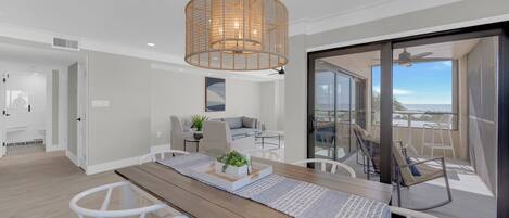 A modern living space with a dining area, a sofa, and a balcony with a view.