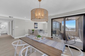 A modern living space with a dining area, a sofa, and a balcony with a view. - Beachfront 2B/2B Sandarac Vacation Condo 506B. Direct gulf view! (Fort Myers Beach)