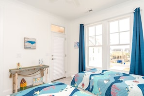 A bedroom with a bed, a dresser, a window with curtains, and a view of a construction site outside. - Relaxin @ The Roses II - Brand New Home with Amazing Sound Views (Surf City)