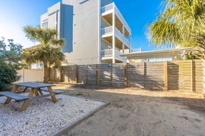 Ein Wohnhaus mit Balkon, Holzzaun und Kiesfläche mit Picknicktisch.