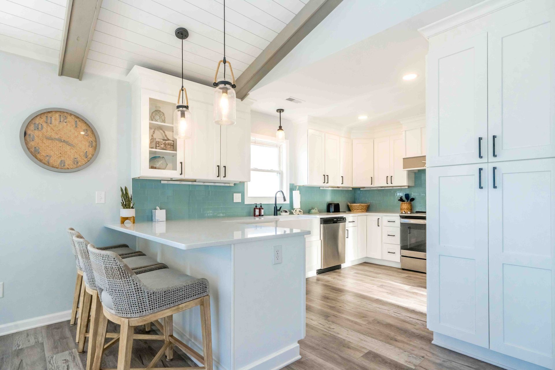 A modern kitchen with white cabinetry, a central island with bar stools, and pendant lighting.