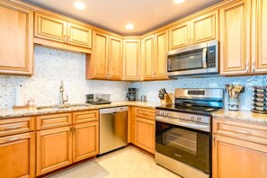 A kitchen with wooden cabinets, a stainless steel microwave, a built-in oven, and a coffee maker. - Good Company - Classic 3BR Oceanfront Beach Cottage with Screen Porch (Topsail Beach)