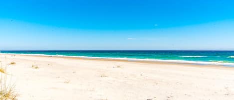 Una playa con cielos despejados y aguas tranquilas.